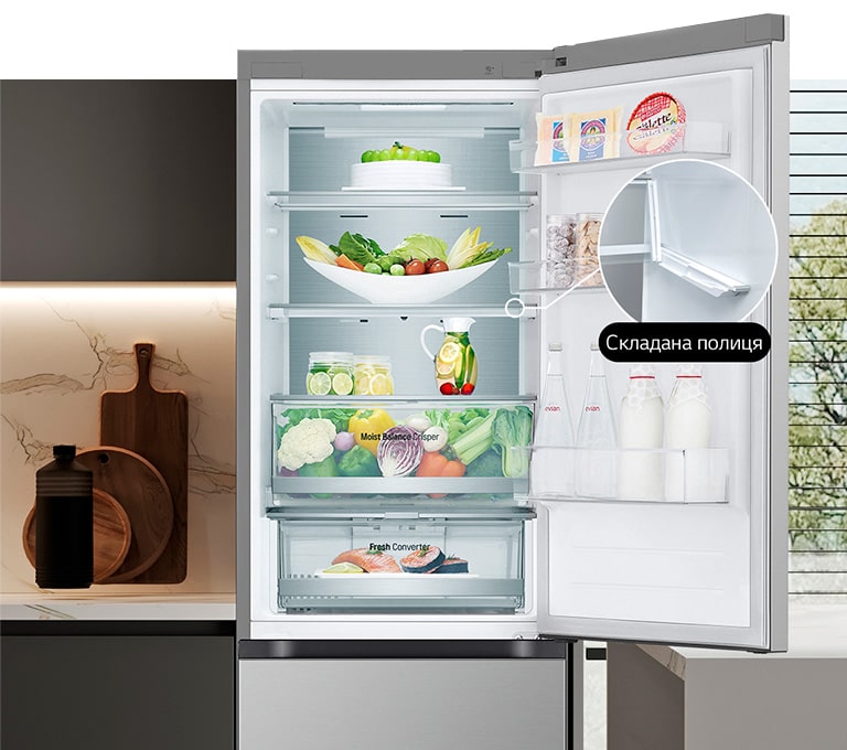  В холодильнику, який наповнений свіжими продуктами, відкриті дверцята, та демонструється наявність винної та складаної полиць.