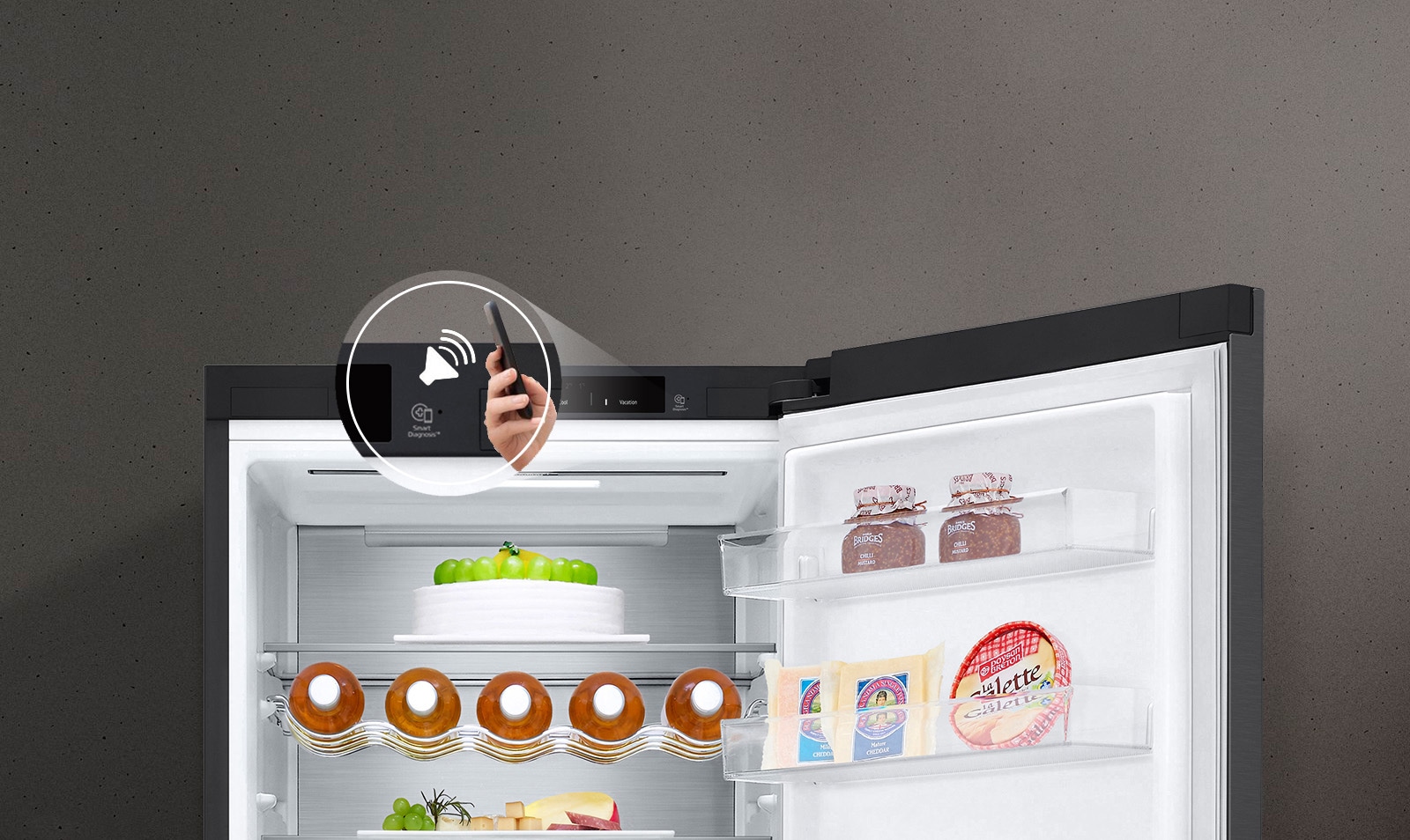 Зображено справа на передньому плану руку, що тримає смартфон, на якому видно інтерфейс моніторингу енергоспоживання в застосунку ThinQ. Позаду зображено інтер'єр кухні з холодильником ліворуч з підсвіченим віконцем InstaView Door-in-Door.