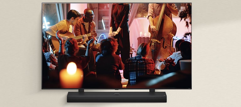 На телевізорі LG грає затишний концерт, а під ним розташований саундбар LG.