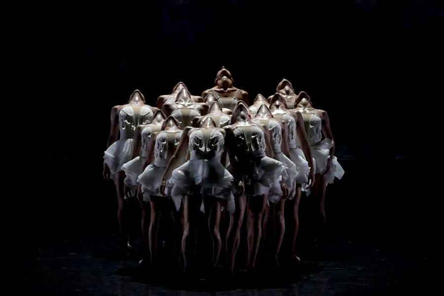 A photo of female dancers on stage with their heads tilted backward.