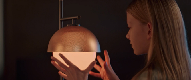 Close-up image of a young girl placing her hands around a lamp which illuminates.