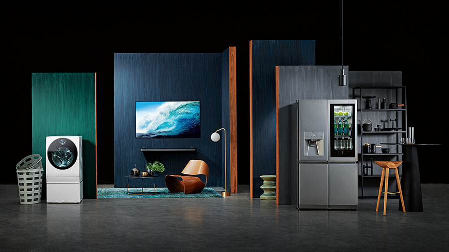 sstarting from the left, lg signature washing machine, oled tv w, refigerator is displayed with some green and blue wall in some place like a dark studio