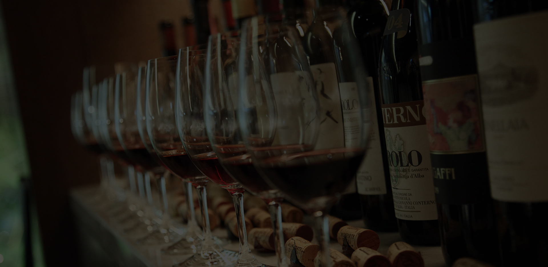 There are a lots of wines and glasses on the bar table.