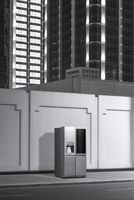 lg signature refrigerator is laid on the night street with building ejecting lights through its windows
