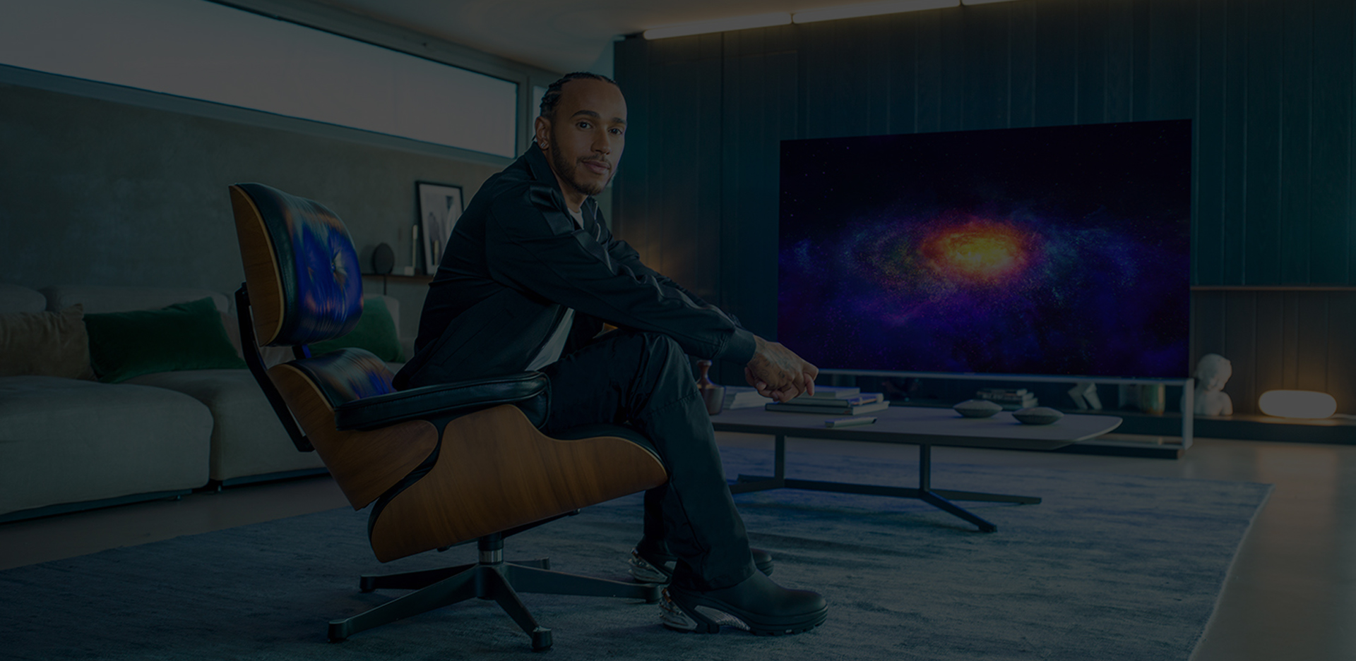 Lewis Hamilton sitting on a couch and behind him is the LG SIGNATURE OLED 8K TV.