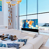 LG SIGNATURE Rollable OLED TV R and Wine Cellar in a white-and-blue-themed room in front of large windows with a view of the ocean.