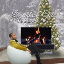 John Legend relaxing in front of an LG Rollable OLED R TV displaying a fireplace set in front of a Christmas tree