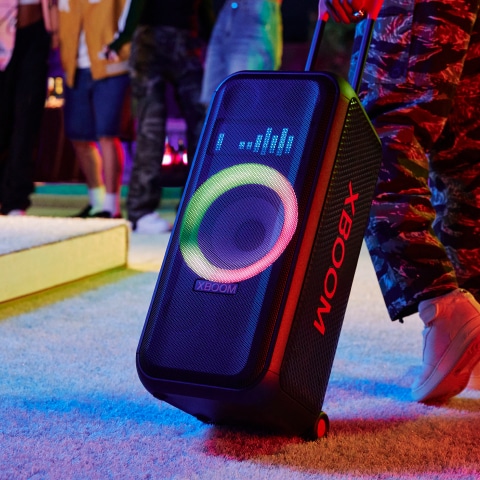 Person using the handle and wheels of the LG XBOOM Portable Tower Speaker to transport their speaker