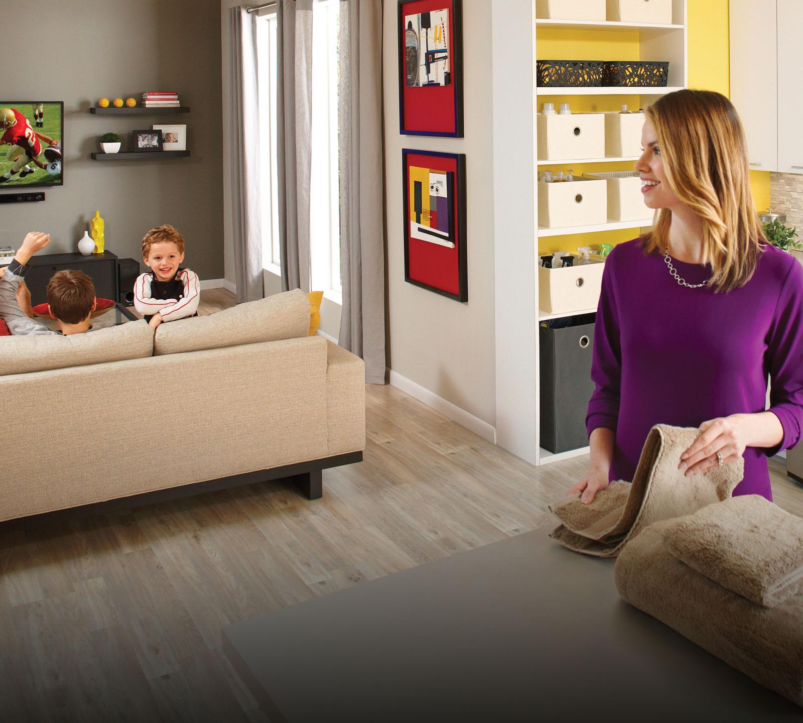 A mom multitasks by folding laundry and enjoying quality time at home with her two boys.