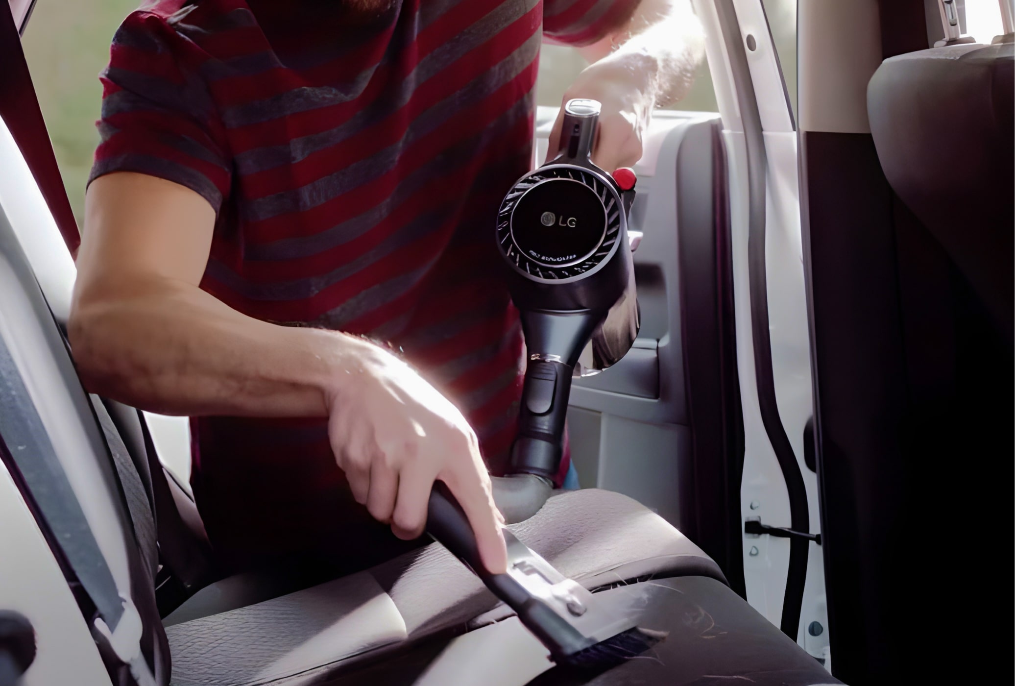Man using LG CordZero vacuum to clean pet hair from car seats