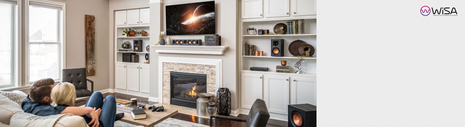 A couple sitting on a couch watching an LG TV on the wall above a fireplace.