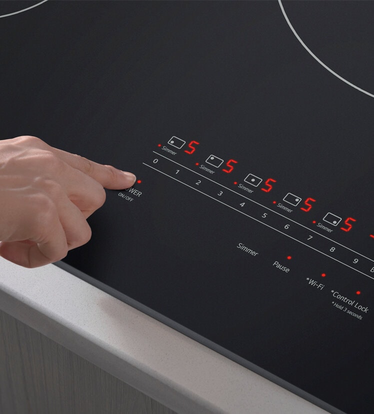 A person using the touch controls of an LG induction cooktop.