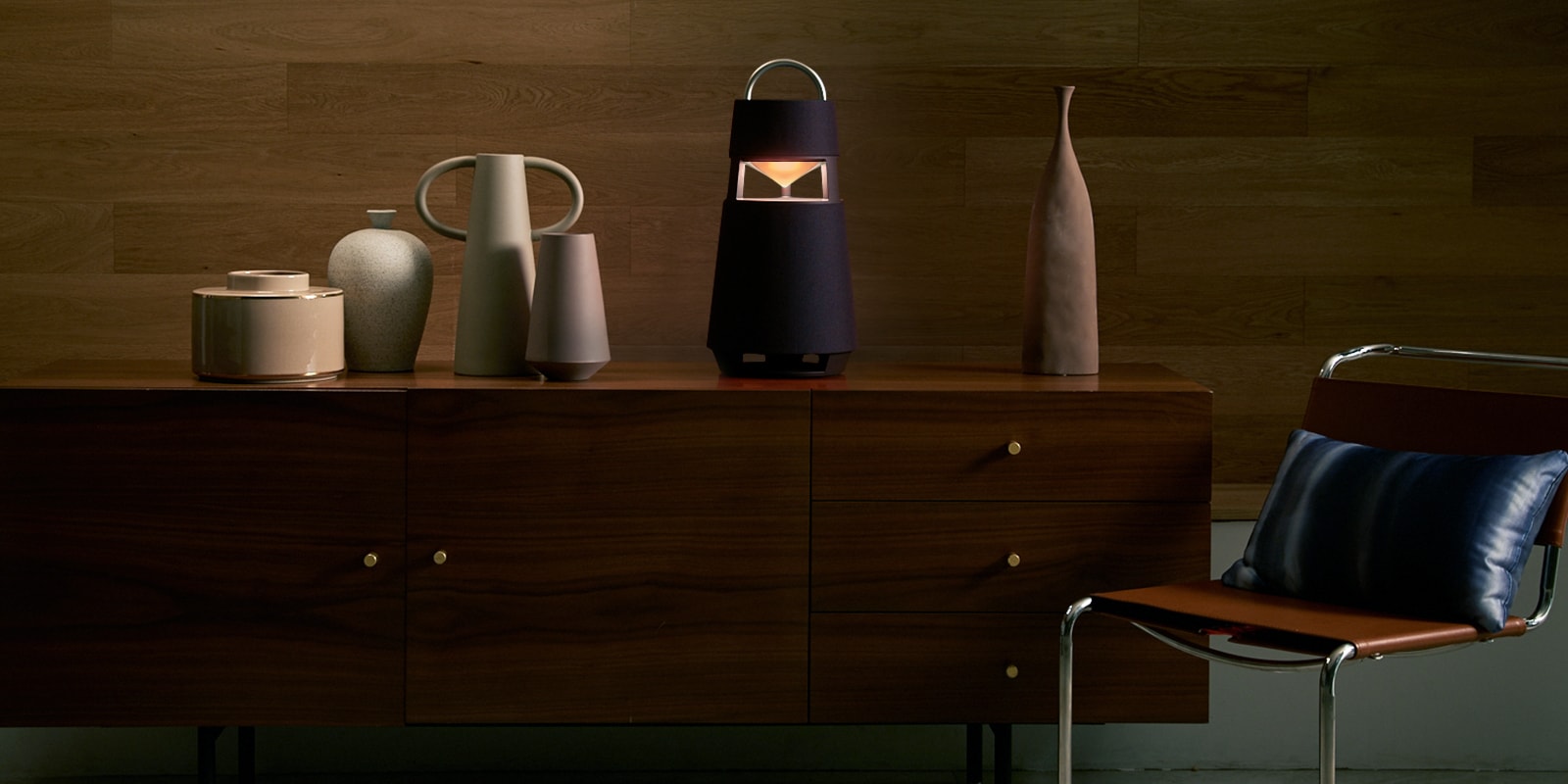 Image of the XBOOM 360 with sculptures on a shelf in a wood-toned interior background.