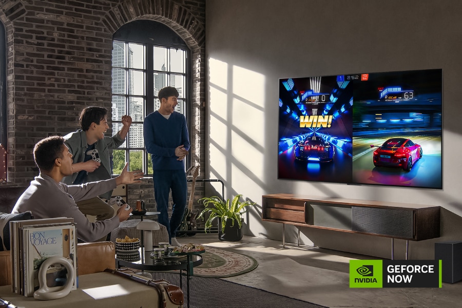 Группа друзей играет в автомобильную гоночную игру на своем телевизоре. Логотип NVIDIA GEFORCE NOW.