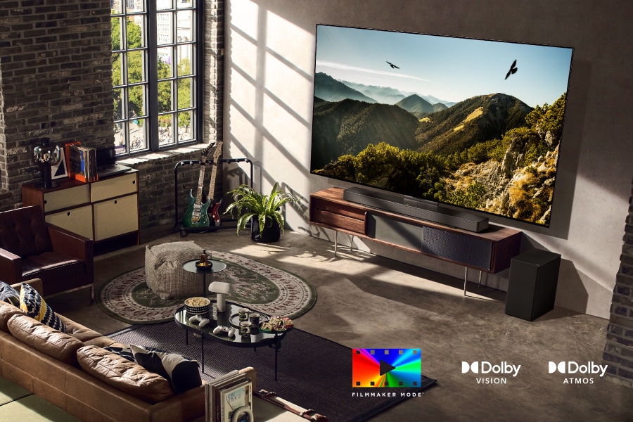 Телевизор в стильной гостиной с двумя орлами, парящими на экране. Логотип FILMMAKER MODE. Логотип Dolby Vision. Логотип Dolby Atmos.
