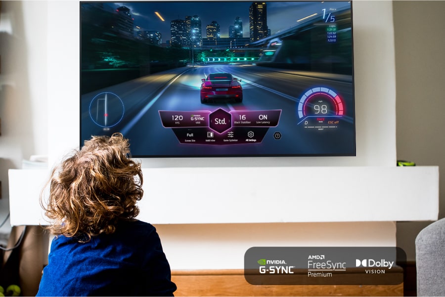 A child playing a video game on the TV. NVIDIA G-SYNC logo. AMD FreeSync Premium logo. Dolby Vision logo.