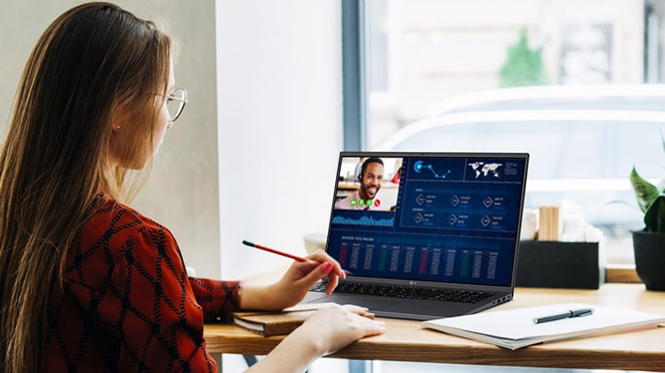 It shows an image of a woman sitting in front of a laptop and videoconferencing using a built-in webcam & speakers.