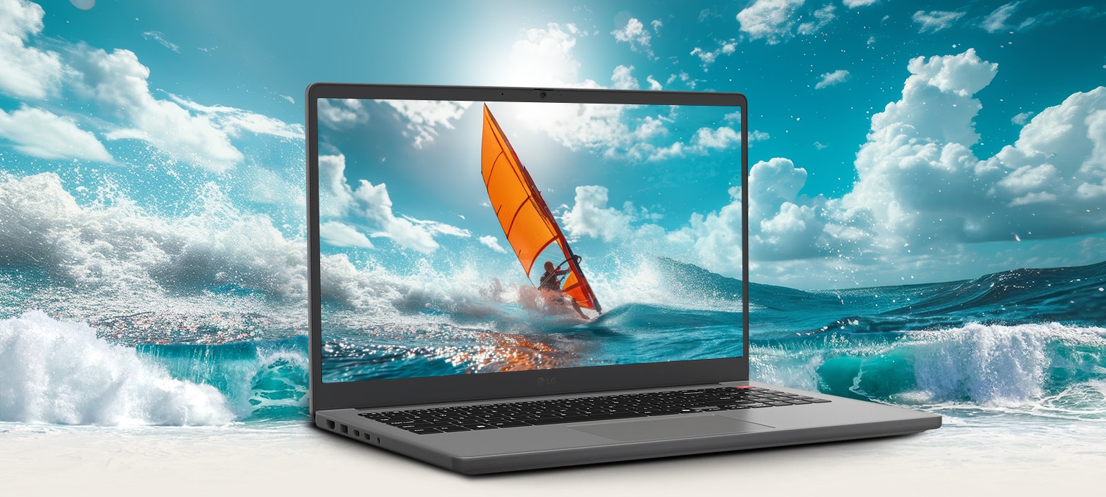 The image features a gray laptop with its screen displaying a vibrant scene of windsurfing on the ocean. The bright, dynamic waves appear to extend beyond the screen, creating a 3D-like effect that blends the display content with the background environment. 