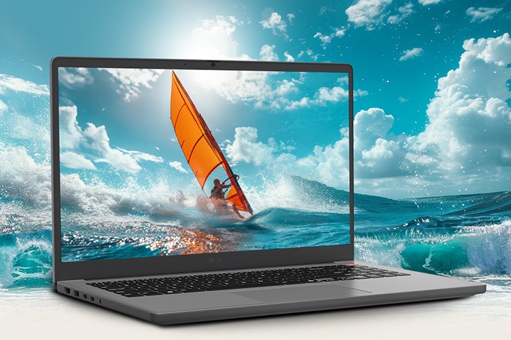 The image features a gray laptop with its screen displaying a vibrant scene of windsurfing on the ocean. The bright, dynamic waves appear to extend beyond the screen, creating a 3D-like effect that blends the display content with the background environment. 
