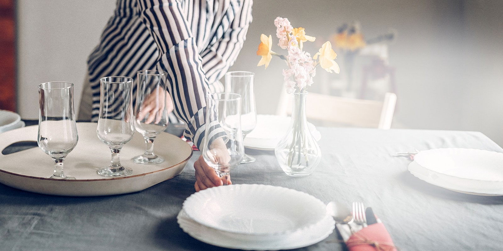 woman setting a dinner table with fresh clean glassware