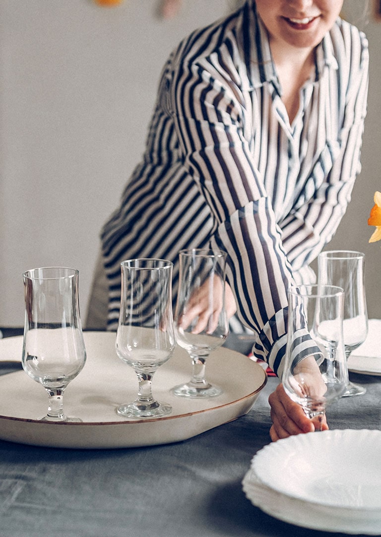 woman setting a dinner table with fresh clean glassware