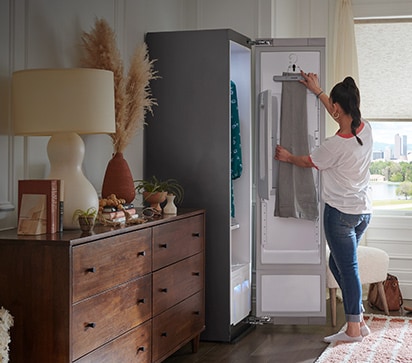 Woman using LG Styler to hang pants to be pressed and restored