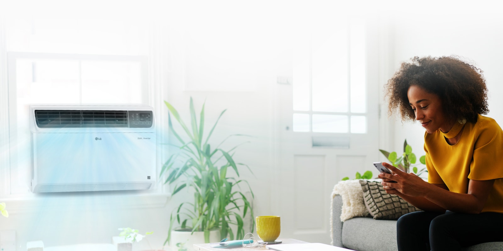 LG Smart AC in living room window and a woman using smart phone on a sofa