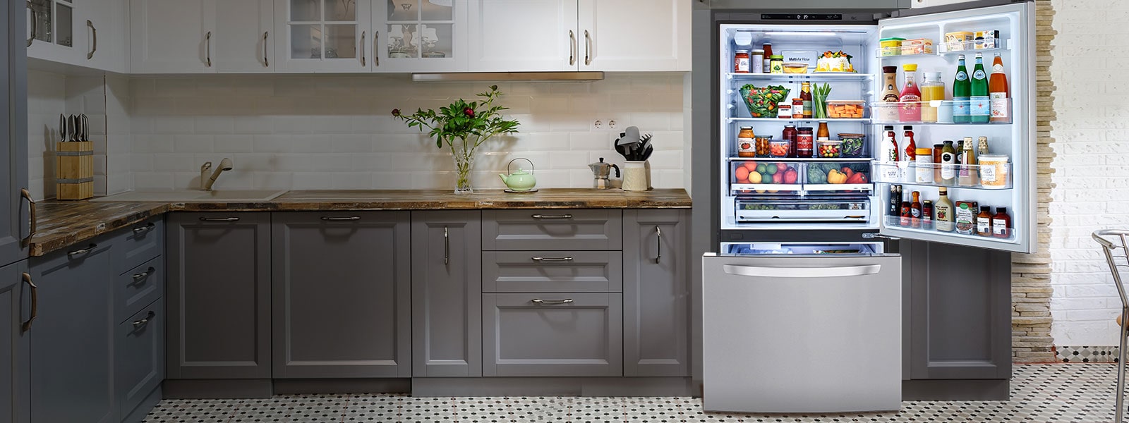 Open LG Refrigerator filled with food highlighted by light in a kitchen