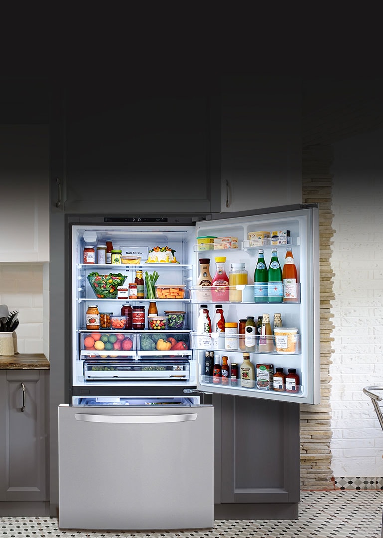 Open LG Refrigerator filled with food highlighted by light in a kitchen