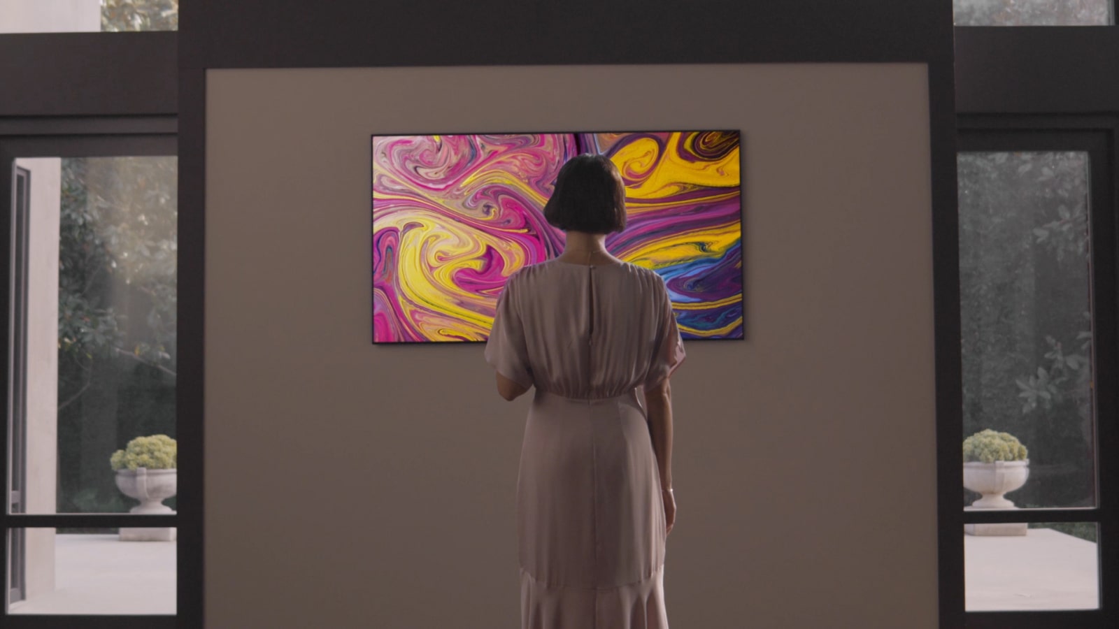 A woman who has a gallery TV wall-mounted in a gallery-like house sees a gallery TV stand and looks at them emotionally