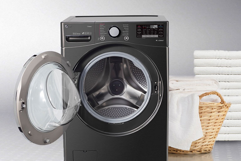 Open front load washer next basket of white towels