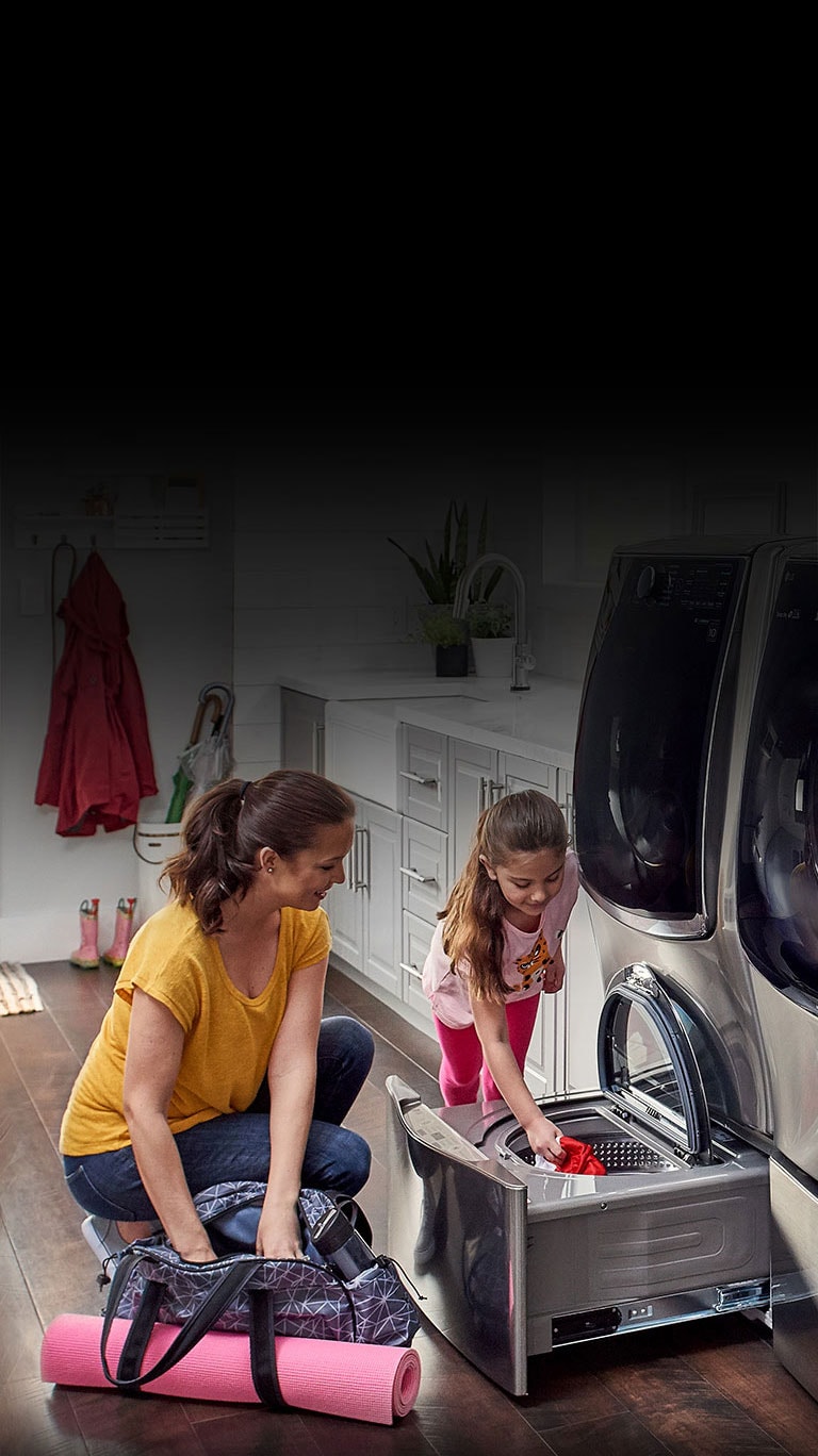 Woman and child placing clothes inside the pedestal washer