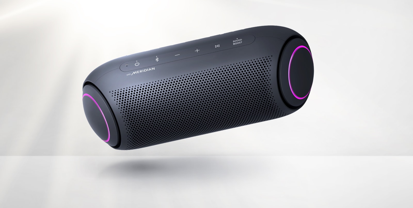 LG XBOOM Go tilts to the left and floats in the air. The woofer lighting is magenta.