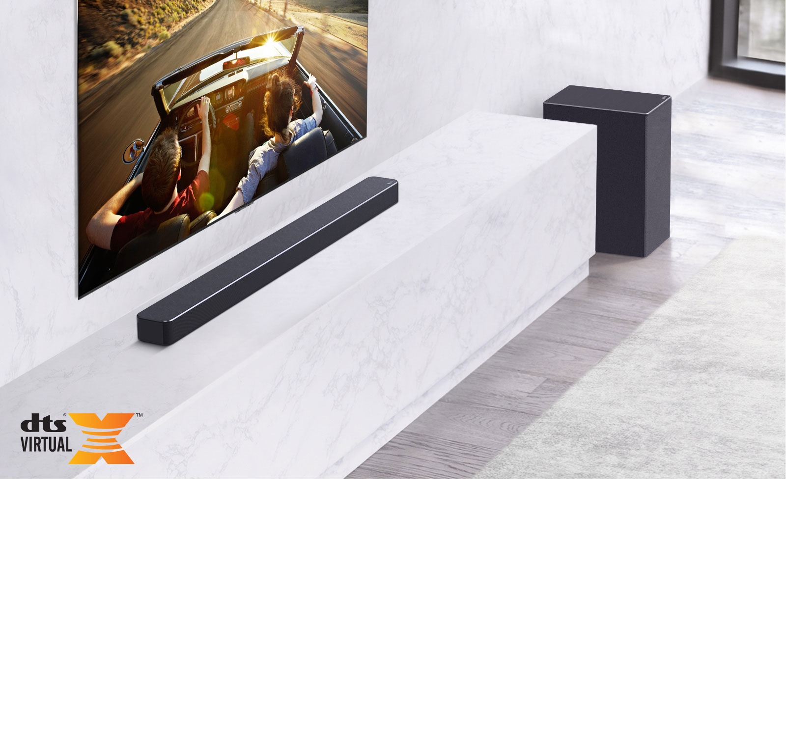 TV is on the wall, LG Soundbar is below on a white marble shelf with a sub-woofer to the right. TV shows a couple in a car. 