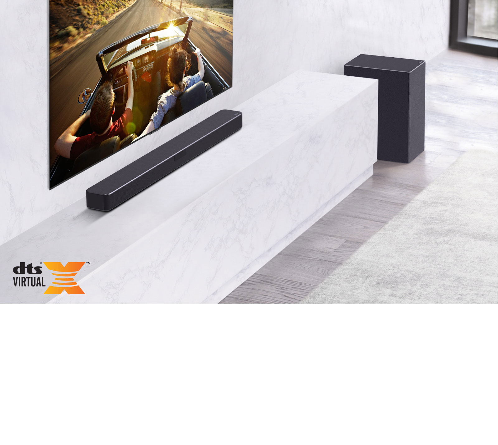 TV is on the wall, LG Soundbar is below on a white marble shelf with a sub-woofer to the right. TV shows a couple in a car.