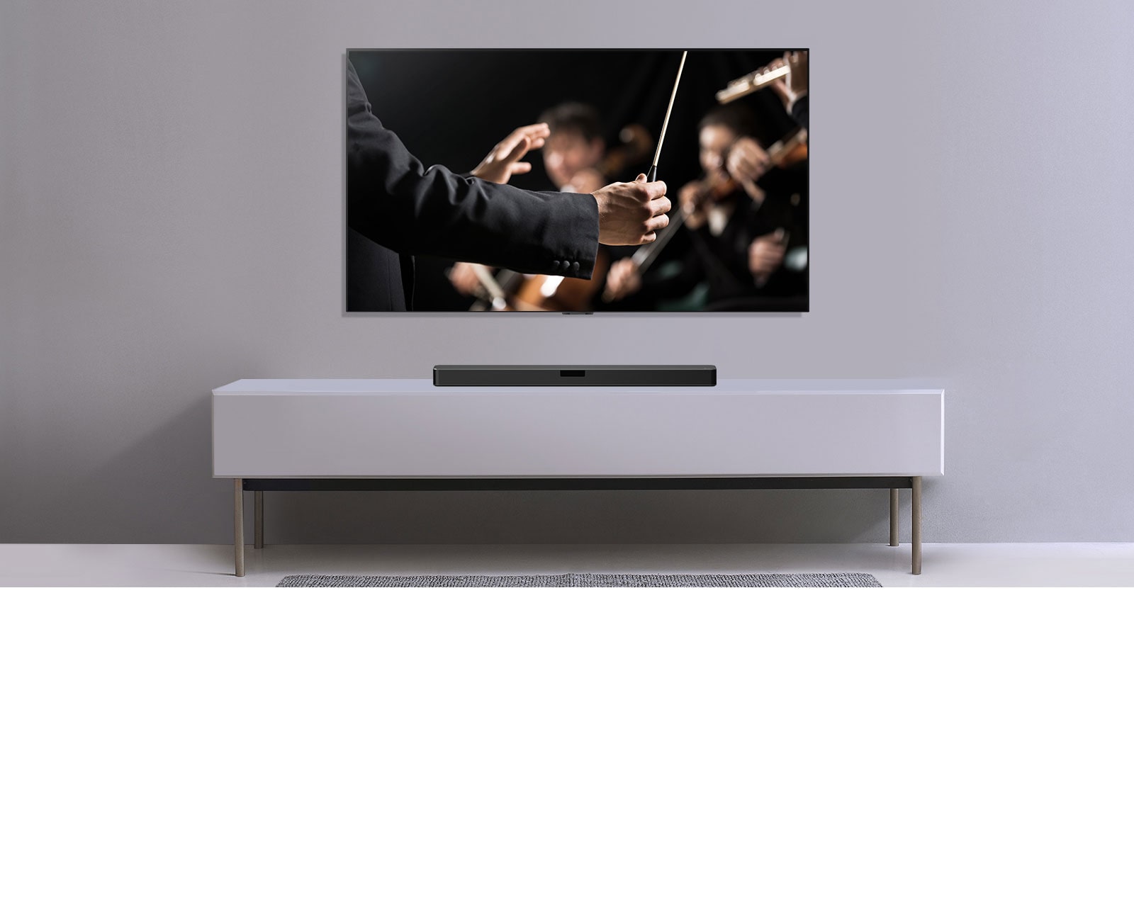 A TV is shown on a gray wall and LG Soundbar below it on a gray shelf. TV shows a conductor conducting an orchestra.