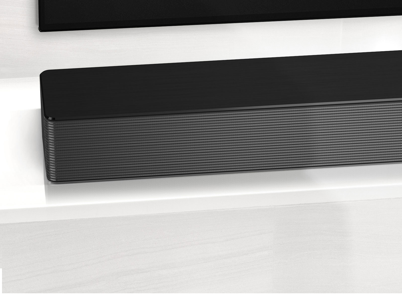 Close-up of LG Soundbar left corner. Bottom left side of TV is also visible.