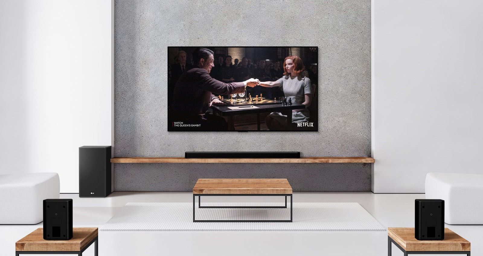 A set of 2 rear speakers, subwoofer, and a soundbar, and TV are in a white living room. A woman and a man are playing chess on TV screen. 