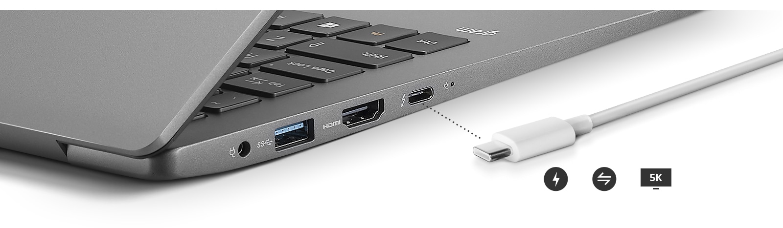 Image of a side view of the laptop with close up of outputs and a charger next to it