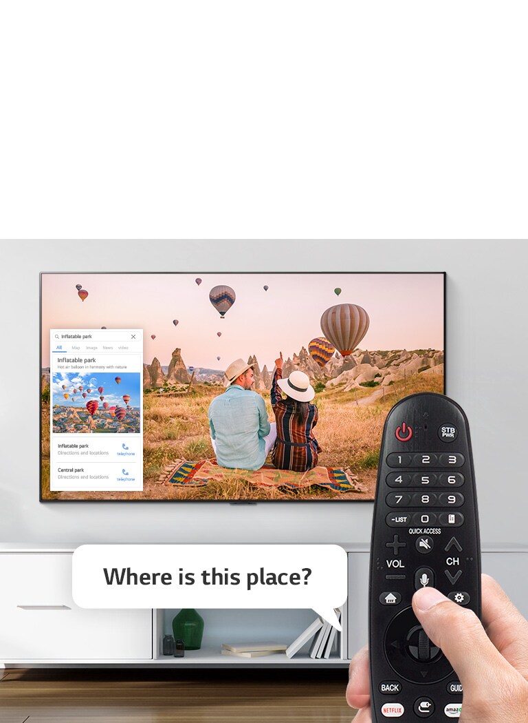 tv on a wall with hand holding remote control
