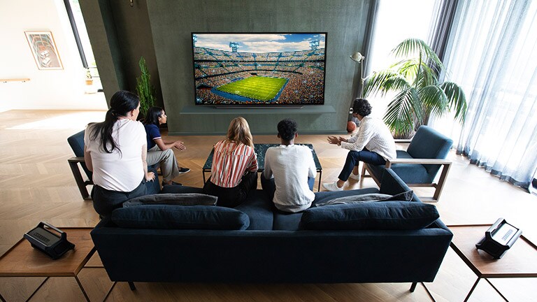 People watching sports game on TV in the living room with Bluetooth rear speakers