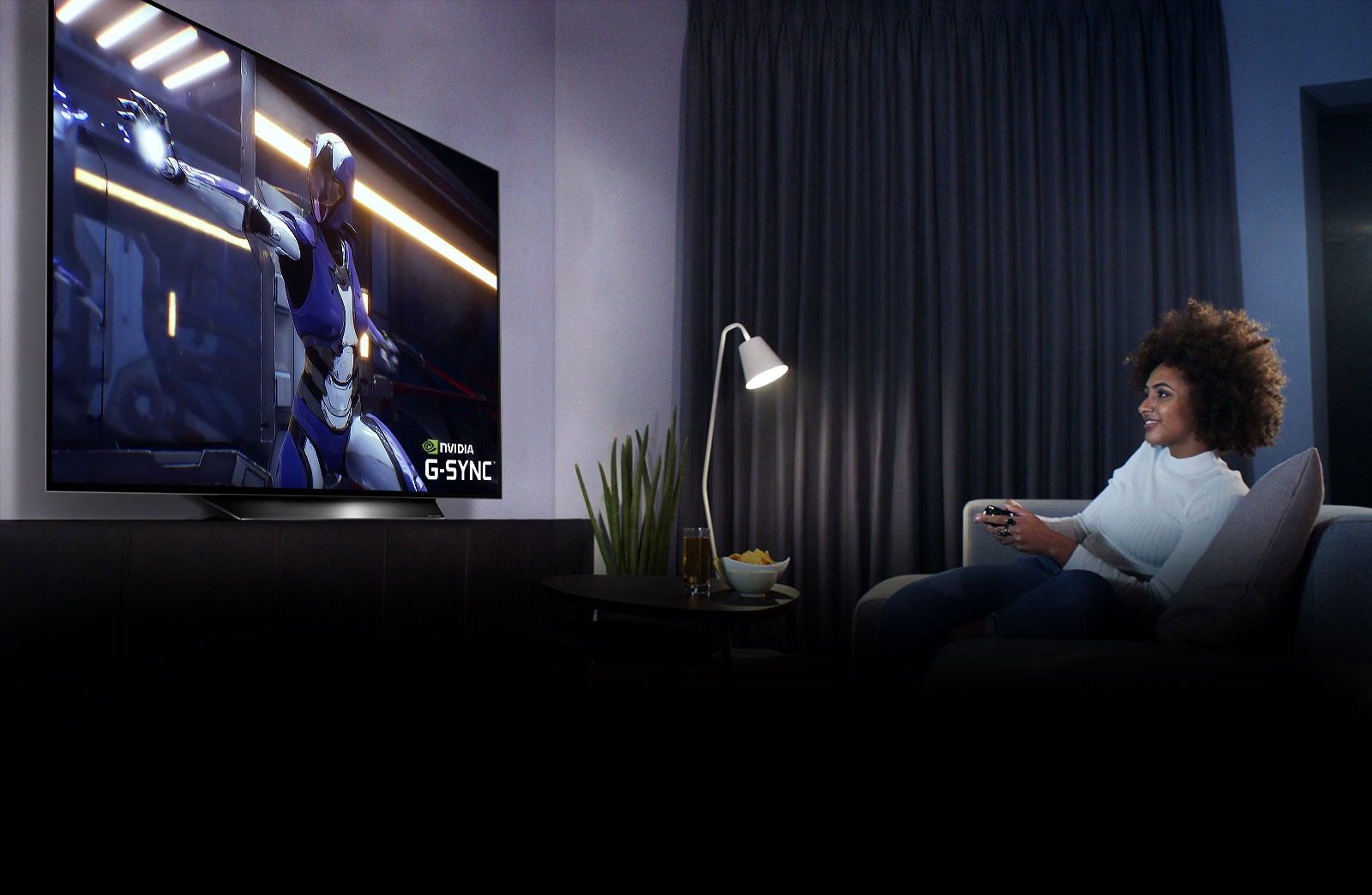 Woman sitting on a sofa, holding a joystick while playing a game on a TV screen