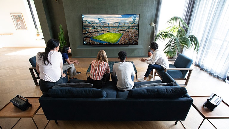 People watching sports game on TV in the living room with Bluetooth rear speakers