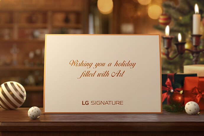 A white holiday card from the LG SIGNATURE is placed on the desk.