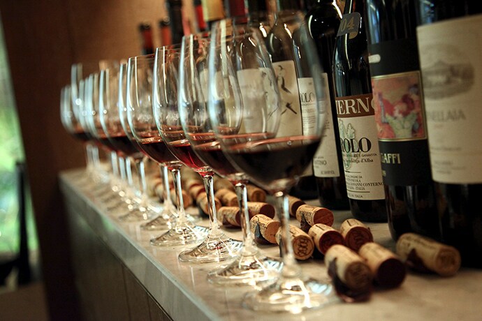 There are a lots of wines and glasses on the bar table.