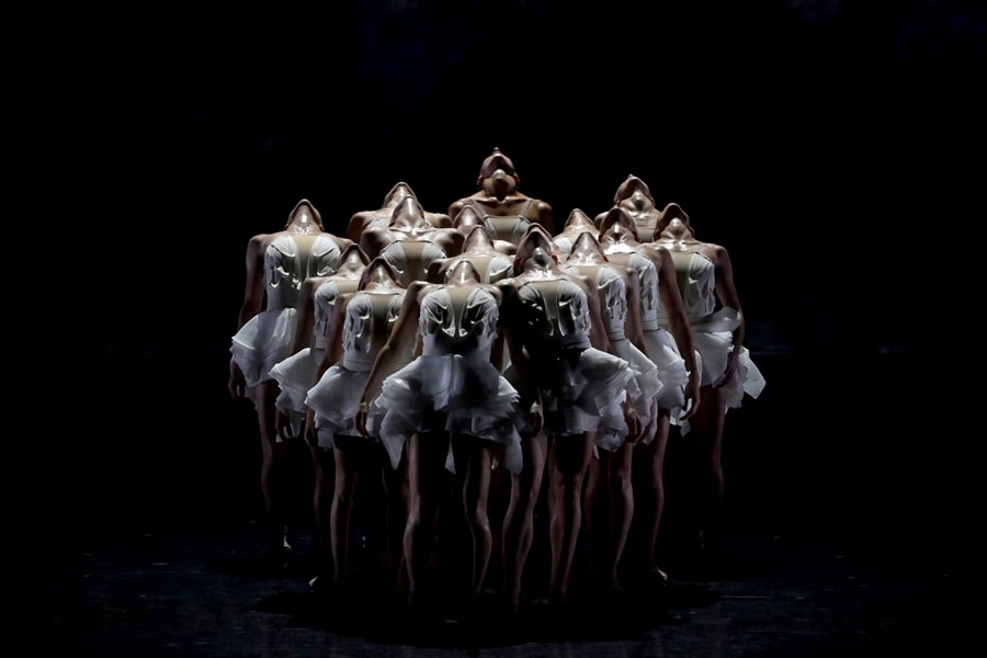 A photo of female dancers on stage with their heads tilted backward.