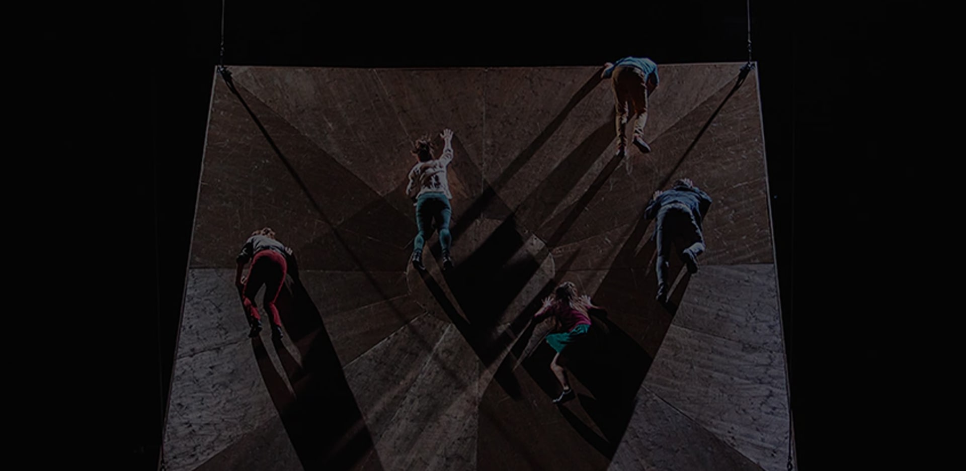 A photo of male and female dancers appearing to fall from an uneven surface.
