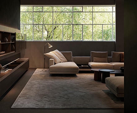 Couches and side tables are arranged in the living room with a long window across the whole wall.