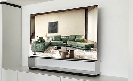 A spacious living room with green couches is displayed on the screen of LG SIGNATURE OLED 8K.