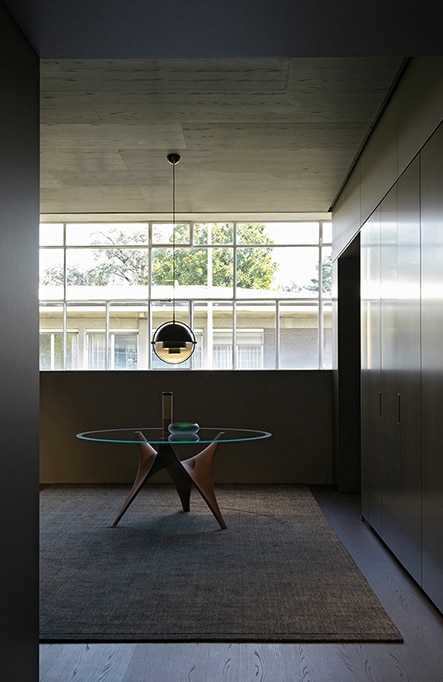 A glass table is placed in the middle of a spacious dining room.